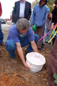 To close out the celebration Michael lowers the time capsule into a hole under a nearby tree. The container is made of clay to be eco friendly.