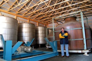 Chris stands in front of an additional load of distilling equipment that recently arrived.