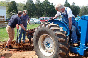 Don Lansing lowers an auger into place from his tractor to dig holes for posts.