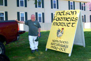 Russ Fisher, local artist and vendor at the market, shows off the recently touched up road sign that sets just off of Route 151 in Nellysford during the market season.