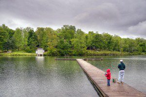 A father and son fish from the pier at Lake Monacan under threatening skies.