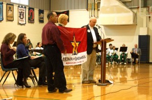 Retired Marine Staff Sgt. Goldie Tomlin (right)  presents a flag to the parents of  Major Michael Martino. Major Martino, a chopper pilot, was killed in a November 2nd 2005 attack on his aircraft. 