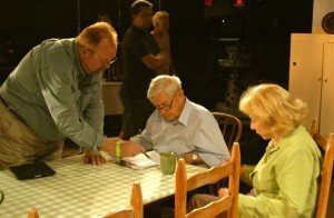Ralph Waite (center seated) who played John Walton in the series and Michael Learned (right) who played Olivia Walton, go over notes with a member of the production staff during the shooting of the reunion series.  